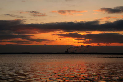 Scenic view of sea against dramatic sky during sunset