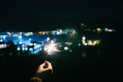 Person holding sparkler at night