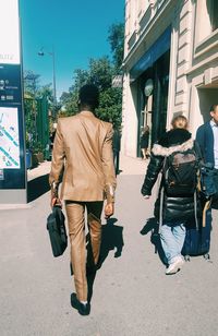 Rear view of men walking on street in city