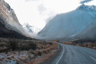 Road amidst snowcapped mountains against sky