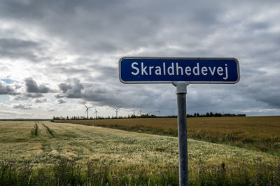 Information sign on field against sky