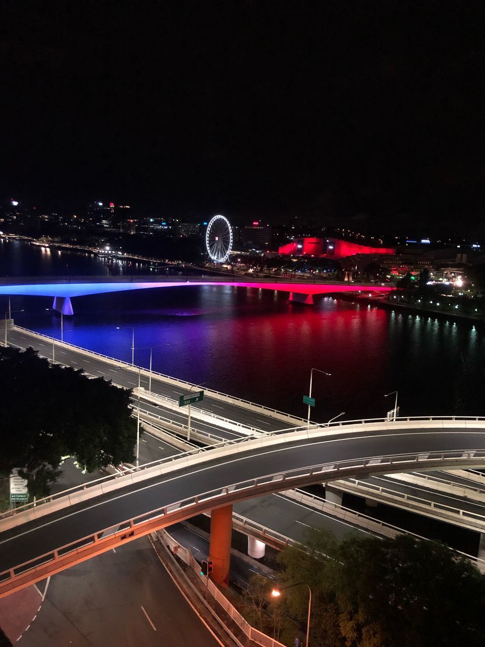 ILLUMINATED BRIDGE OVER RIVER AGAINST SKY AT NIGHT