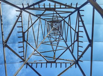 Low angle view of electricity pylon against blue sky