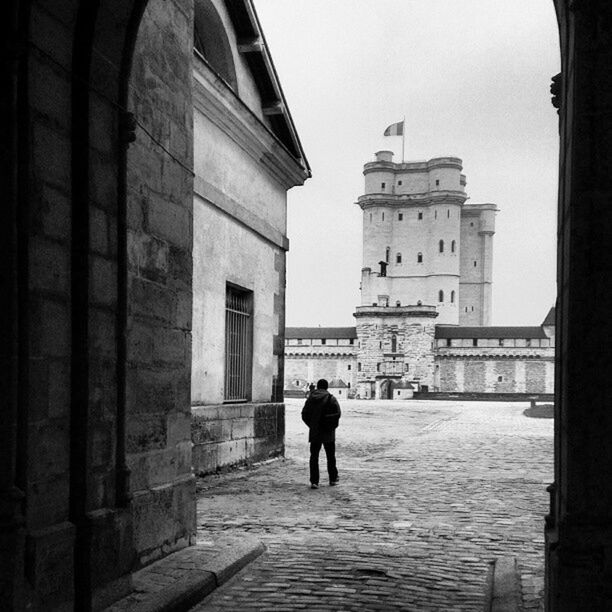 architecture, building exterior, built structure, walking, full length, men, rear view, street, building, city, the way forward, lifestyles, old town, person, sky, cobblestone, history, residential building