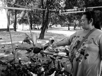 Mature woman feeding birds in park