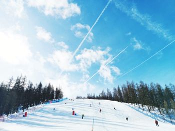Panoramic view of people on snow covered land against sky