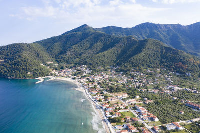 Aerial view of city by sea against sky