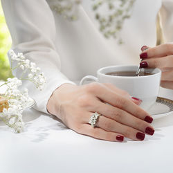 Midsection of woman holding coffee on table