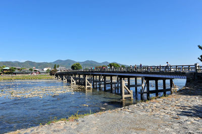 Pier over river against clear blue sky