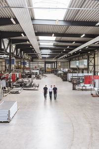 Three men walking and talking on factory shop floor