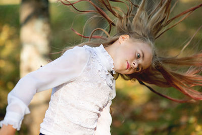 Cute girl tossing hair while standing in park