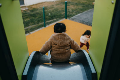 Rear view of boy sitting on slide