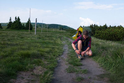 Rear view of woman sitting on land against sky