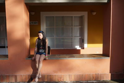 Portrait of woman sitting against window of building