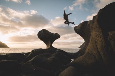 Scenic view of man jumping from cliff