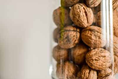 Close-up of walnuts in jar against white background