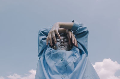 Low angle portrait of woman with glitter on face against sky