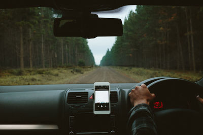 Cropped hands of man driving car on road