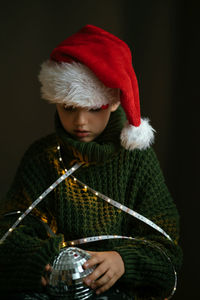 Cute boy in green sweater and santa hat, sad