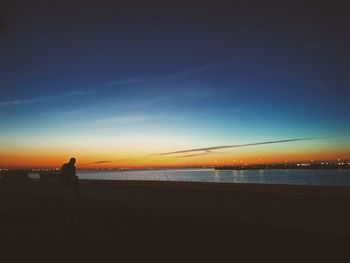 Silhouette man on beach against sky at sunset