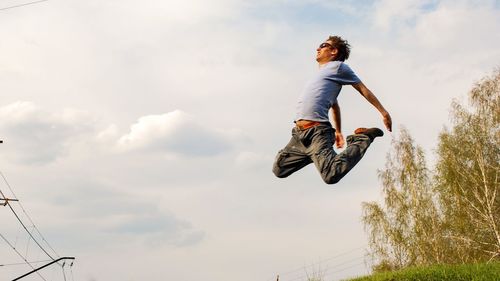 Low angle view of man jumping against sky