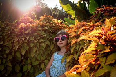 Portrait of young woman with sunglasses on leaves