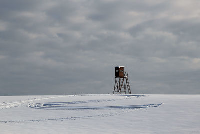 Crane on snow covered land against sky