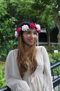 Portrait of smiling young woman standing against trees