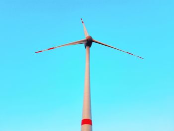 Low angle view of wind turbine against clear blue sky