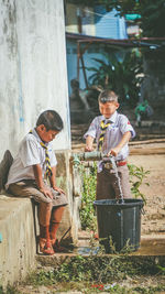 Water pouring in bucket from faucet amidst schoolboys