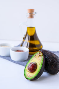 Olive oil in glass bottle with sesame and flax seeds. fresh ripe hass avocado. 