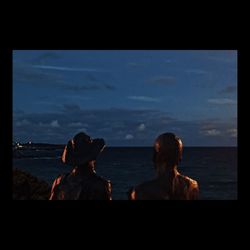 Rear view of people at beach against sky