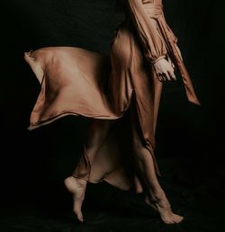 Low section of woman dancing against black background