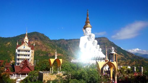 Statue by temple against sky