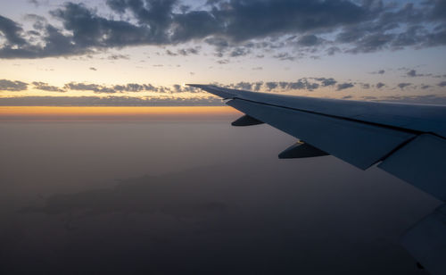 Airplane wing against sky during sunset