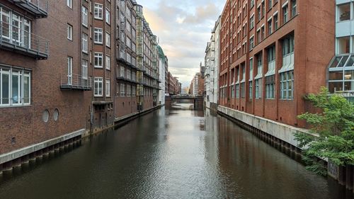 Canal amidst buildings against sky