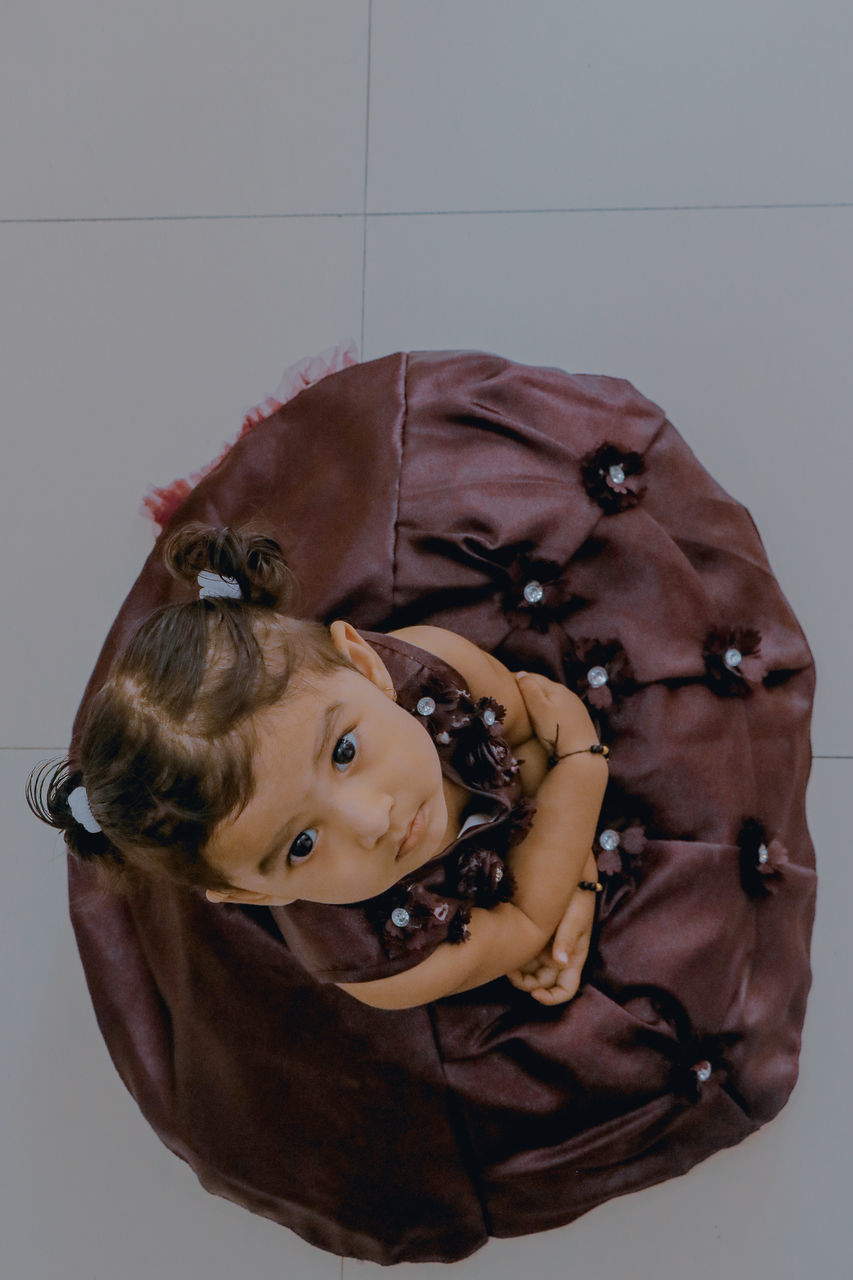 PORTRAIT OF A GIRL WITH BLACK HAIR AGAINST WHITE BACKGROUND