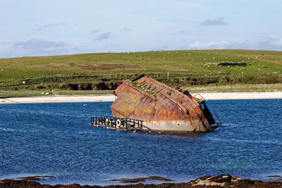 Abandoned boat in sea against sky