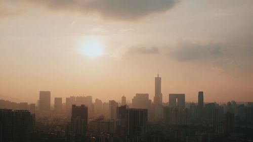 Modern buildings in city against sky during sunset