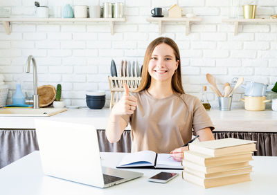 Portrait of smiling young woman using laptop on table