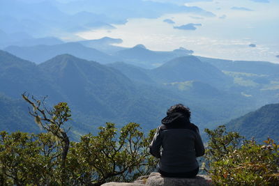 Rear view of woman looking at mountains against sky