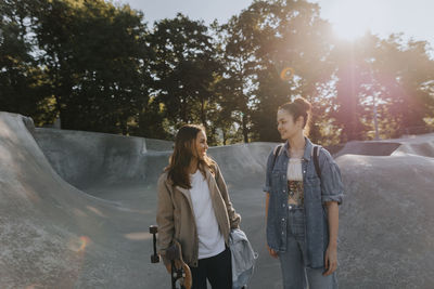 Smiling teenage girls talking together at skate park