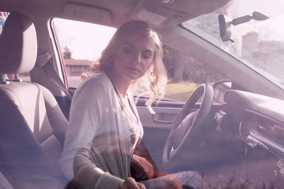 Young woman sitting in car seen through window