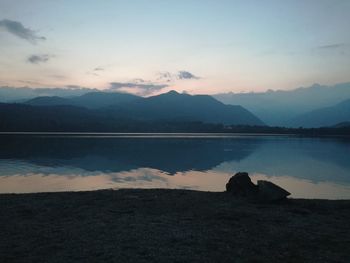 Scenic view of lake and mountains against sky at sunset