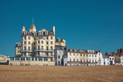 Victorian hotel buildings on the seafront in eastbourne under a clear blue sky