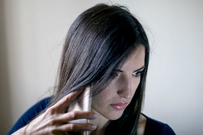 Close-up of woman talking on mobile phone against white background