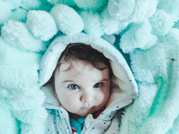 Portrait of cute baby lying on bed wrapped in blanket