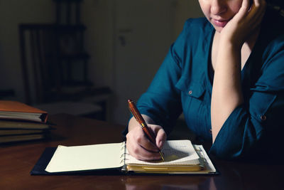 Midsection of woman reading book on table