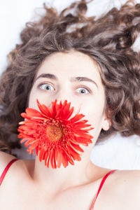 Close-up portrait of woman with red flower on face