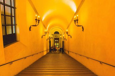 Rear view of women walking in illuminated corridor